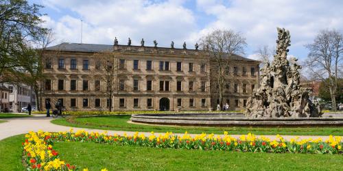 Frontalansicht des Erlanger Schloss mit bunten Frühjahrsblumen im Vordergrund