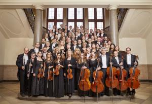 Die Musiker der Jenaer Philharmonie mit ihren Instrumenten. Sie sind elegant in schwarz-weiß gekleidet.