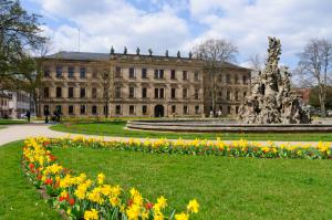 Frontalansicht des Erlanger Schloss mit bunten Frühjahrsblumen im Vordergrund