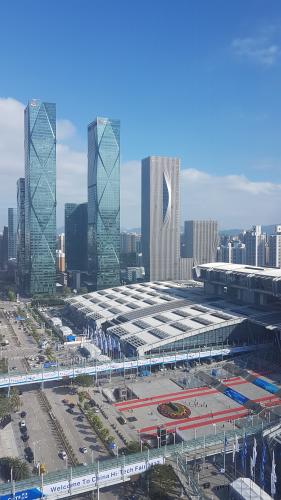 Im Hintergrund Panyus Wolkenkratzer mit gläsernen Fassaden. Davor das Messegelände mit Willkommensbanner zur Hi-Tech Messe 2017
