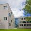 Das Staatliche Berufsbildende Schulzentrum Jena-Göschwitz mit grau-gläserner Fassade und in grüner Umgebung