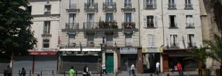 Eine Häuserfront im französischen Aubervilliers. Im Erdgeschoss sieht man verschiedene Läden, datunter eine Brasserie oder einen Tabakladen, die aber allesamt geschlossen sind