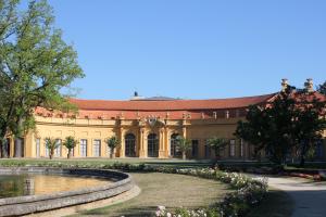 Frontalansicht der Orangerie im Schlossgarten Erlangen. Davor ein Stück vom Brunnen und Rosenbeete 