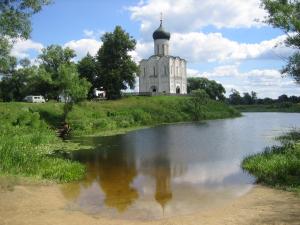 Zu sehen ist die weiße Mariä-Schutz-und-Fürbitte-Kirche an der Nerl im Grünen