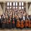 Die Musiker der Jenaer Philharmonie mit ihren Instrumenten. Sie sind elegant in schwarz-weiß gekleidet.